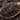 Close-up of loose Organic Assam black tea leaves in a wooden spoon, showing their rich dark brown color and twisted texture.