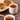 Cup of Organic Dandelion Tea on a wooden surface beside a small dish of honey with a honey dipper, and bowls of loose dried herbs in the background on a wood slab.
