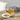 Cup of tea with a bowl and wooden spoon of loose herbal blend beside a teapot and sprigs of lavender on a rustic wooden surface.