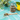 Glass jar and wooden spoon filled with loose Organic Live Fit Tea on a turquoise tile surface, surrounded by lemons and green leaves.