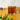 Glass mug filled with Organic Adaptogen Tea, a rich amber-hued blend, set on a golden surface with soft greenery and a jar of loose leaf tea in the background.