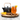Glass of Organic Orange Cinnamon Spice tea garnished with an orange slice, beside a black and gold teapot, cinnamon sticks, orange wedges, and a small bowl of loose tea on a wood slab.