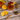 Glass of iced tea garnished with an orange slice and metal straw, surrounded by orange slices, cinnamon sticks, and loose tea on a rustic wooden surface.