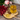 Cup of Organic Heartburn Relief Tea with golden yellow hue, placed on wooden slab beside dried herbal blend in a spoon, surrounded by red and pink flowers on rustic wood background.
