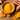 Close-up of vibrant yellow turmeric powder in a wooden bowl surrounded by fresh turmeric roots on a rustic wooden surface.