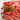 Close-up of vibrant red dried goji berries spilling from a wooden bowl onto a rustic wooden surface, symbolizing a nutrient-rich adaptogenic ingredient.