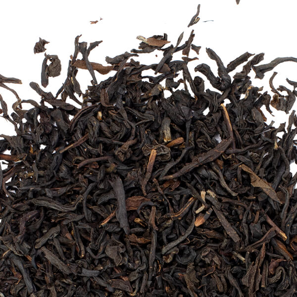 Close up view of loose leaf black tea on a white surface. 