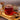 Glass mug of chaga mushroom tea on a wooden tray with cinnamon sticks and a wooden spoon.