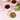 Two cups of tea and a bowl of dried chickweed on a pink surface with green leaves.