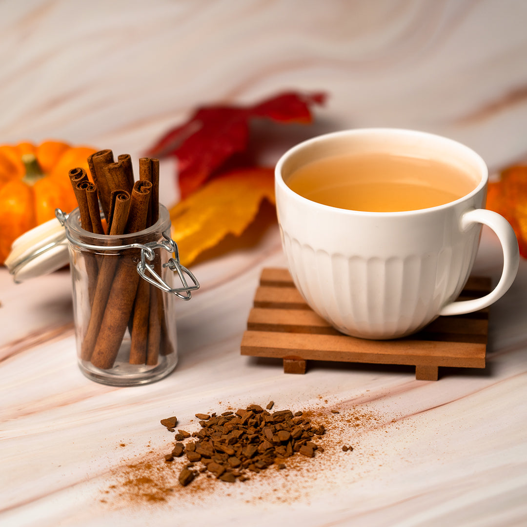 White mug of cinnamon tea with cinnamon sticks and ground cinnamon on a wooden surface