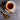 Teacup with floral saucer, cinnamon sticks, and a wooden spoon with tea leaves on a gray surface.