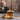Glass cup of tea with a teapot, wooden spoon, and bowl of tea leaves on a wooden surface.
