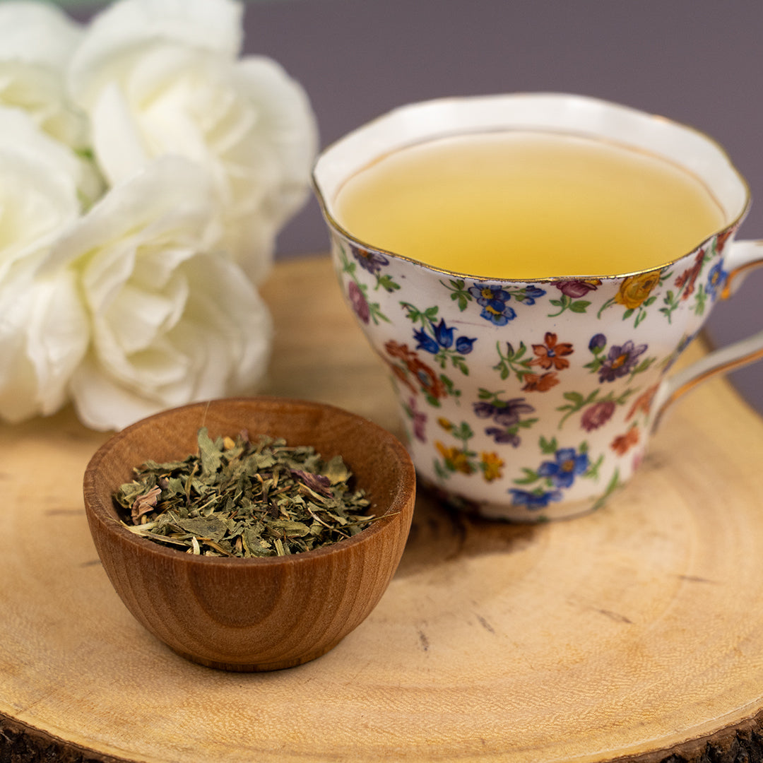 Cup of Organic Echinacea Tea in a floral teacup with dried echinacea leaves in a wooden bowl on a wooden tray.