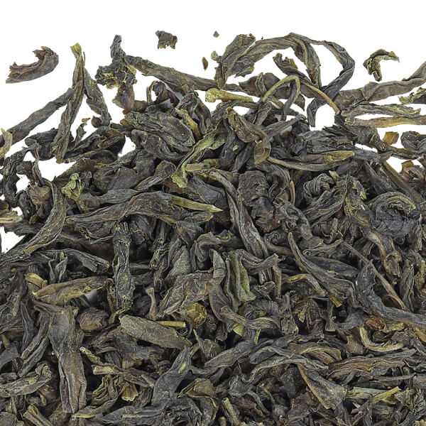Close up view of green tea leaves on a white surface. 