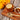 Tea cup with lemon slice, honey, and tea leaves on a wooden board with yellow flowers in the background.
