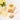 Glass of lemongrass tea with lemon slices, cinnamon sticks, and a plant on a white surface