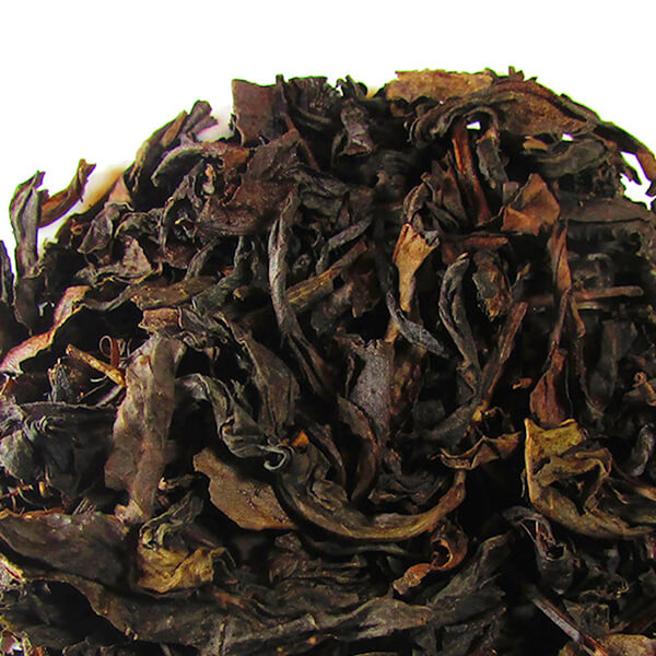 Close up view of loose leaf oolong tea on a white surface. 