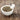 Mortar and pestle filled with dried blessed thistle herbs beside scattered seeds on a wooden surface.