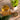 Glass of tea with a bowl of tea leaves and a potted plant on a wooden surface