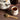 Thyme tea inside a tea cup with thyme leaves beside it in a wooden spoon on a wooden surface. 