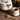 Tea set with marbled teapot, cup, wooden spoon, and thyme leaves on a wooden surface.
