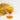 Glass of turmeric tea next to turmeric powder and golden leaves on a white background