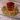 A clear double-walled glass filled with brewed Organic Fresh Start Tea, surrounded by loose herbal tea leaves and chamomile flowers on a rustic wooden surface.