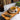 Tea cup with saucer on a wooden tray, surrounded by tea leaves and a teapot, with a blurred bookshelf in the background.