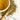 A cup of brewed Organic Yerba Mate tea beside a wooden spoon engraved with ‘Full Leaf Tea Co.’, surrounded by loose yerba mate leaves on a white marble surface.