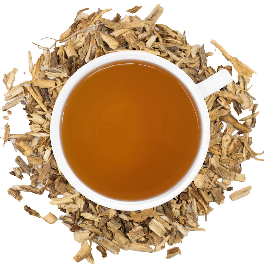 A white mug filled with chicory root tea surrounded by chicory root