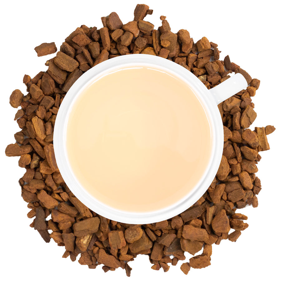 a white mug filled with cinnamon tea surrounded by cinnamon root.