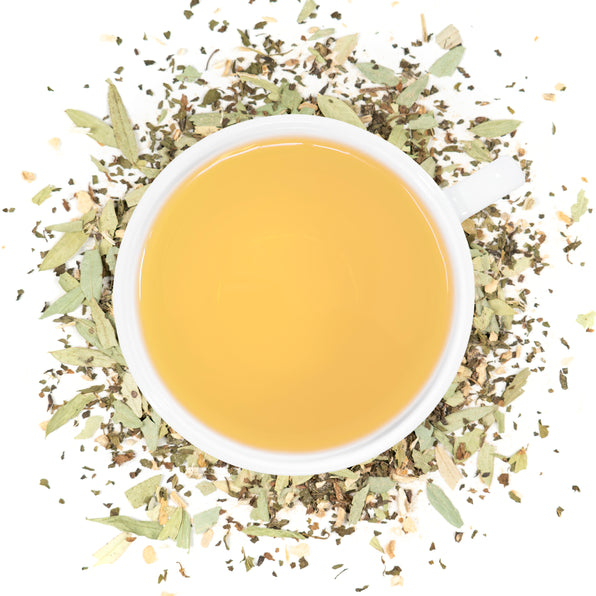 A white cup of Organic Constipation Relief tea surrounded by the loose leaf blend.