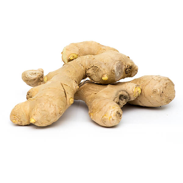 Ginger roots spread out on top of each other on top of a white surface. 