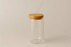 Clear glass jar with a wooden lid and straw on a beige background