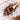 A wooden spoon filled with loose honeybush tea leaves on a white wooden surface, with more tea scattered around.