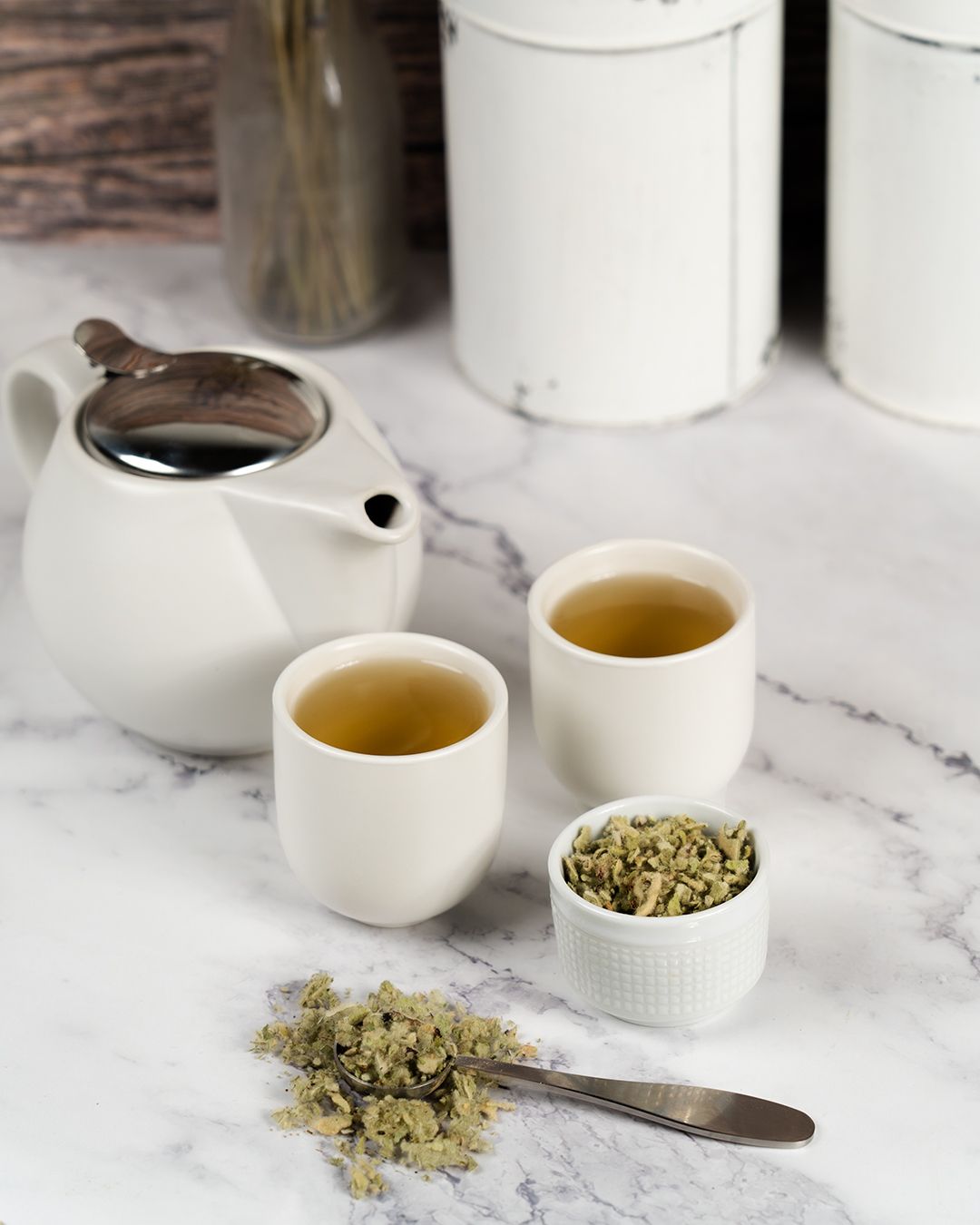 Mullein tea prepared in two cups with mullein herbs around beside them in another cup. 