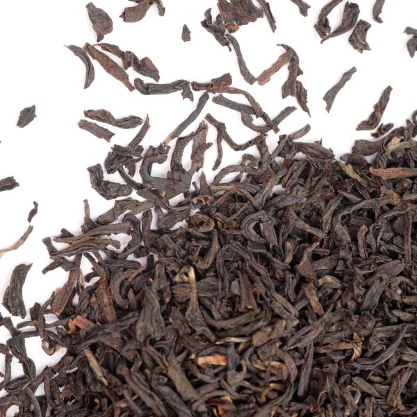 A close up image of pu-erh tea herbs spread out on top of a white surface. 