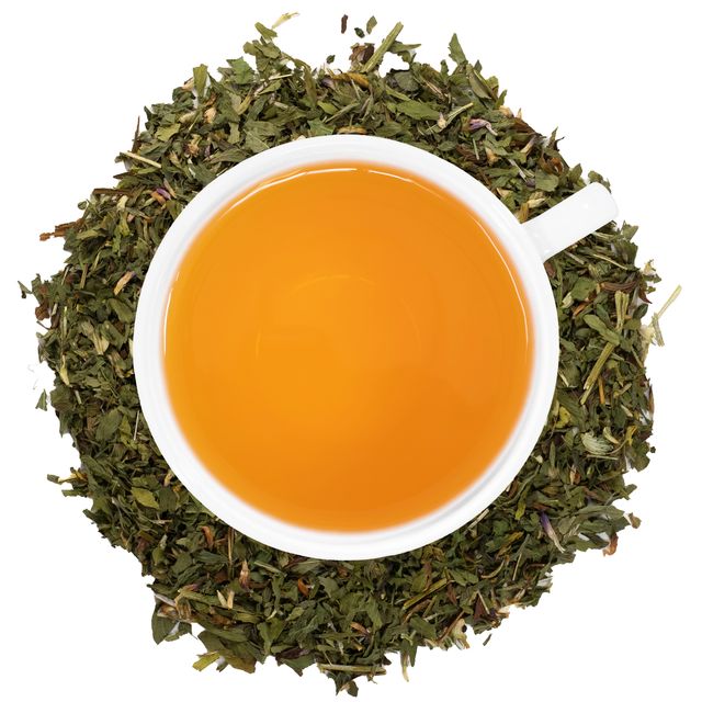 A white cup with Organic Red Clover tea surrounded by the loose leaf tea.