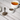 Vitex berries in a small white bowl and metal scoop beside a cup of brewed herbal tea on a light wood table.